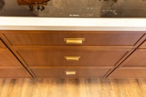 "Custom kitchen with brown cabinets, sleek handles, and practical shelving."